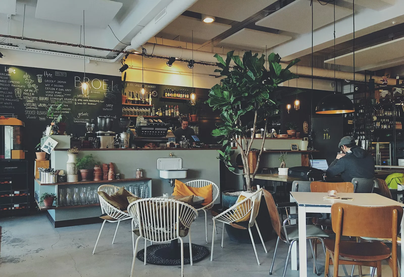 Modernes Café mit Tafelwand, Pflanzen und Sitzgruppen